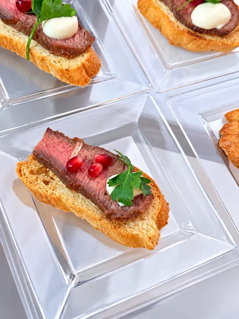 Beef crostini on clear individual plates